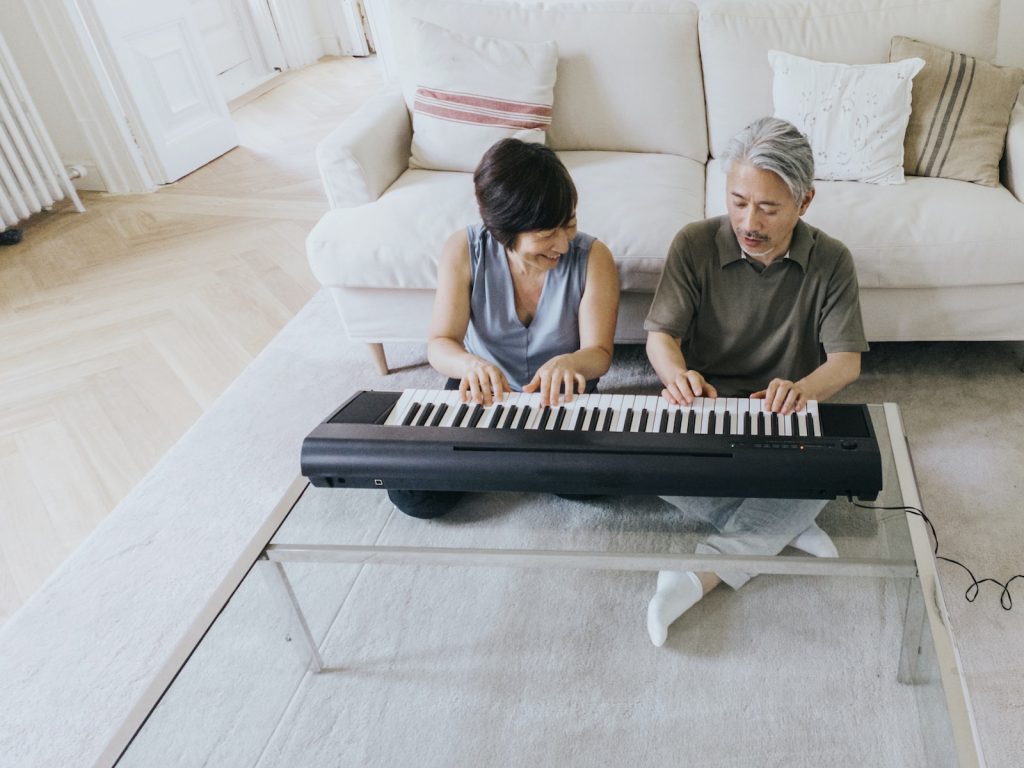 A man and a woman playing a piano on a couch