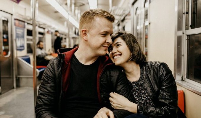 woman hugging man while sitting inside train